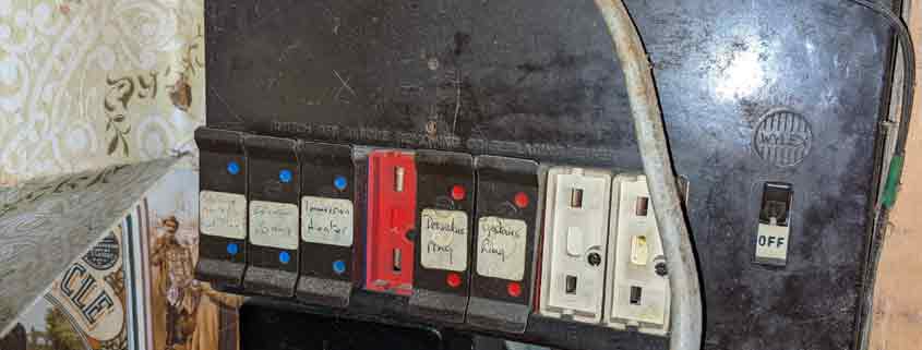 Emergency electrician inspecting an old fuse board